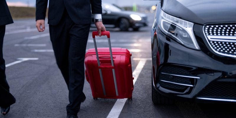Business couple walking with a suitcase on parking lot